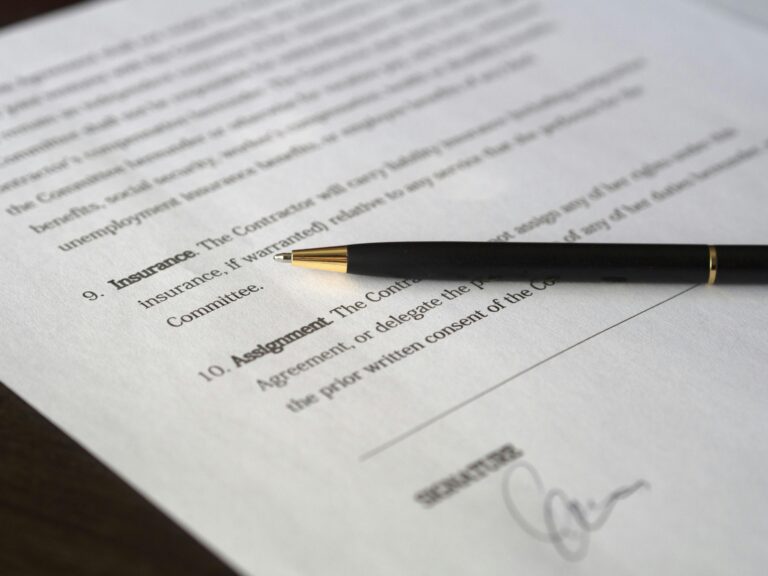 Close-up of a business insurance contract with a pen, emphasizing the importance of reviewing and updating insurance policies for growing businesses.