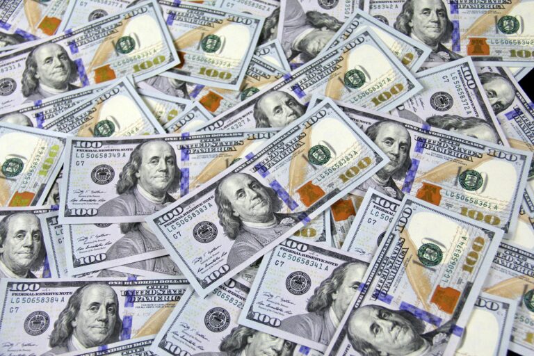 Stack of $100 bills representing rising homeowner’s insurance costs and financial impact of higher premiums due to risk factors like dogs, pools, claims, and poor home maintenance.
