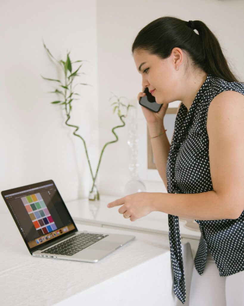 Entrepreneur running a home-based business from a laptop while talking on the phone, emphasizing the importance of business insurance not covered by standard homeowner's policies.