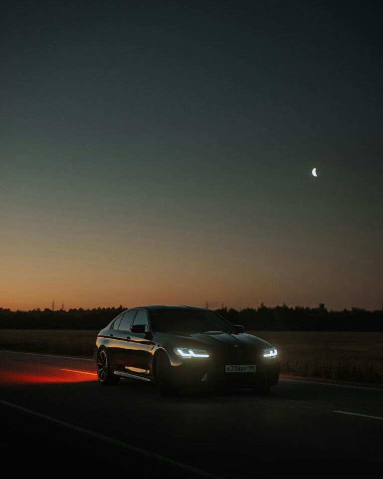 Car driving at night on a rural road with headlights on, illustrating the risks and safety tips for nighttime driving.
