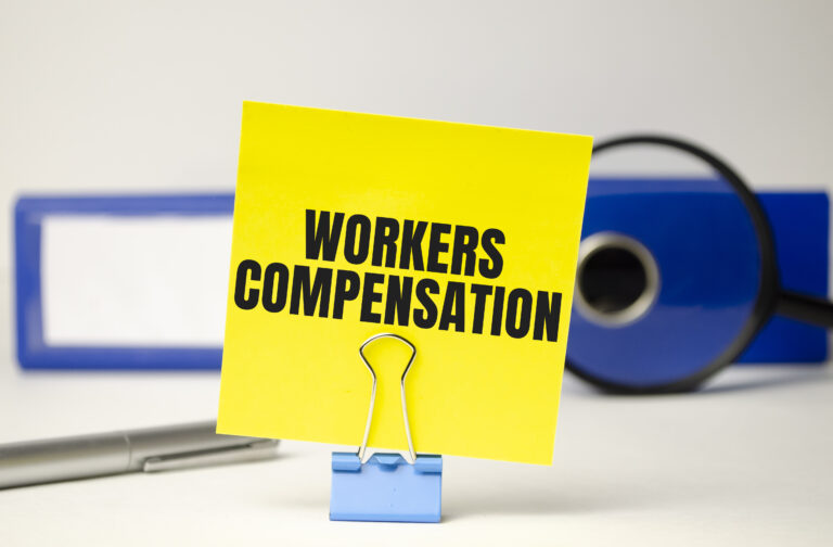 Workers’ Compensation notice on yellow paper with office supplies, illustrating proposed 11.2% rate hike in California for 2025 due to rising medical costs and claims frequency