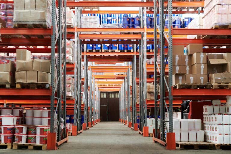 Warehouse shelves stocked with boxes, barrels, and containers, illustrating supply chain inventory challenges and the importance of managing stock during tariff-related disruptions.